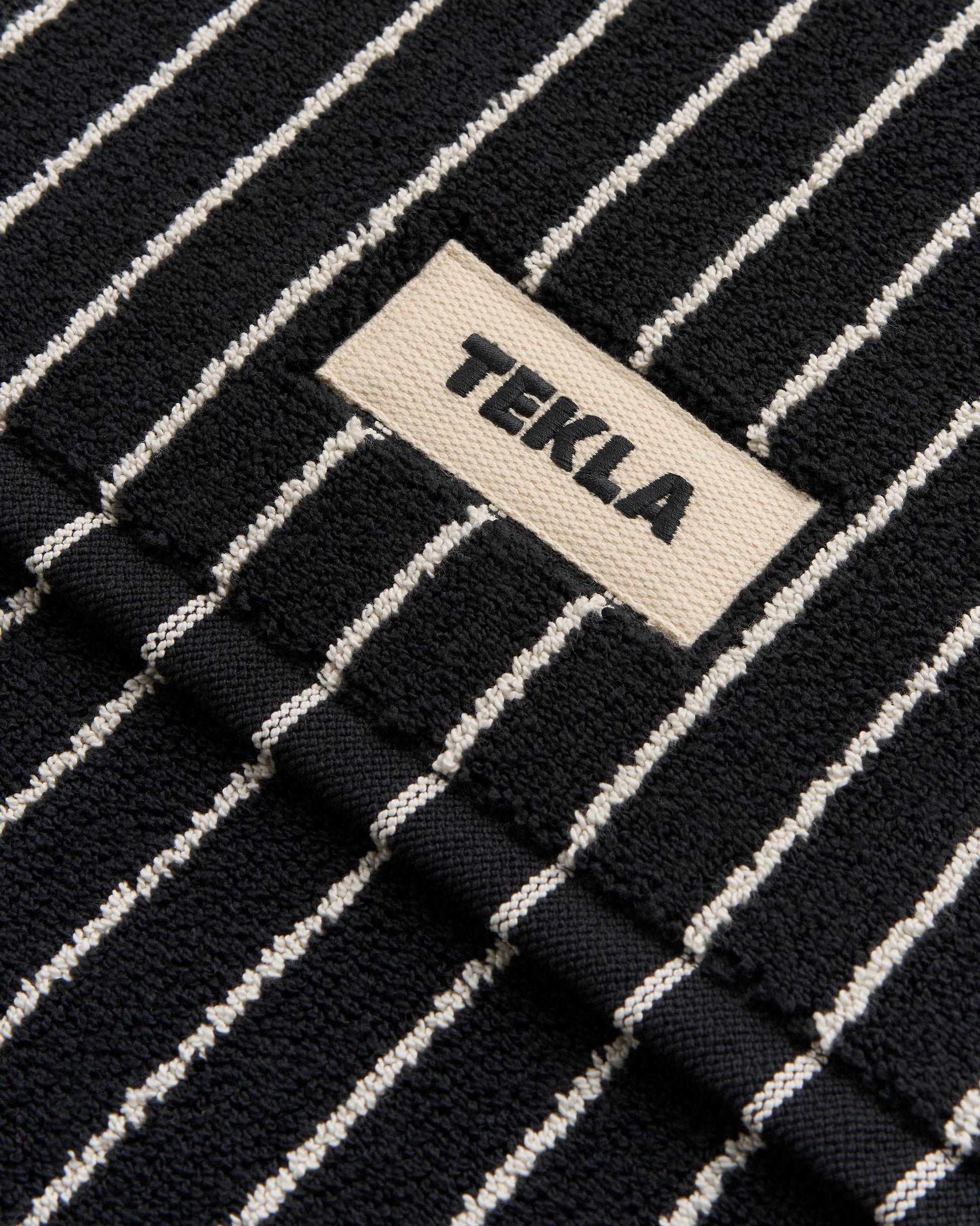 Close-up of a black and white striped fabric with a 'Tekla' label.