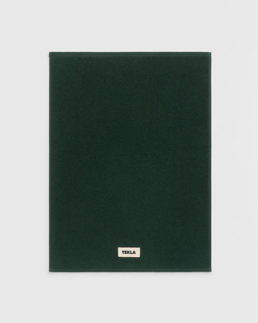 Dark green blanket with 'Tekla' label on a light gray background