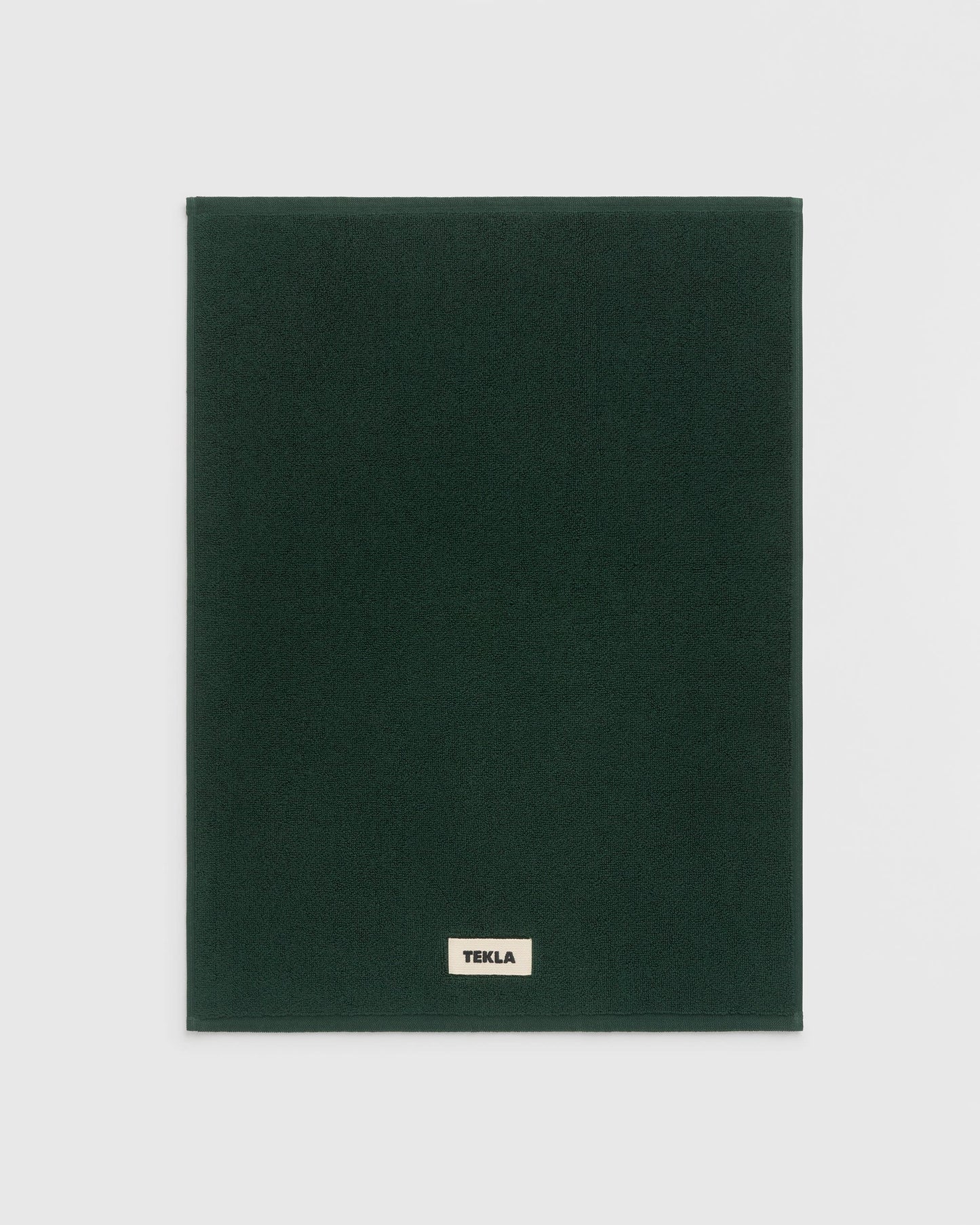 Dark green blanket with 'Tekla' label on a light gray background