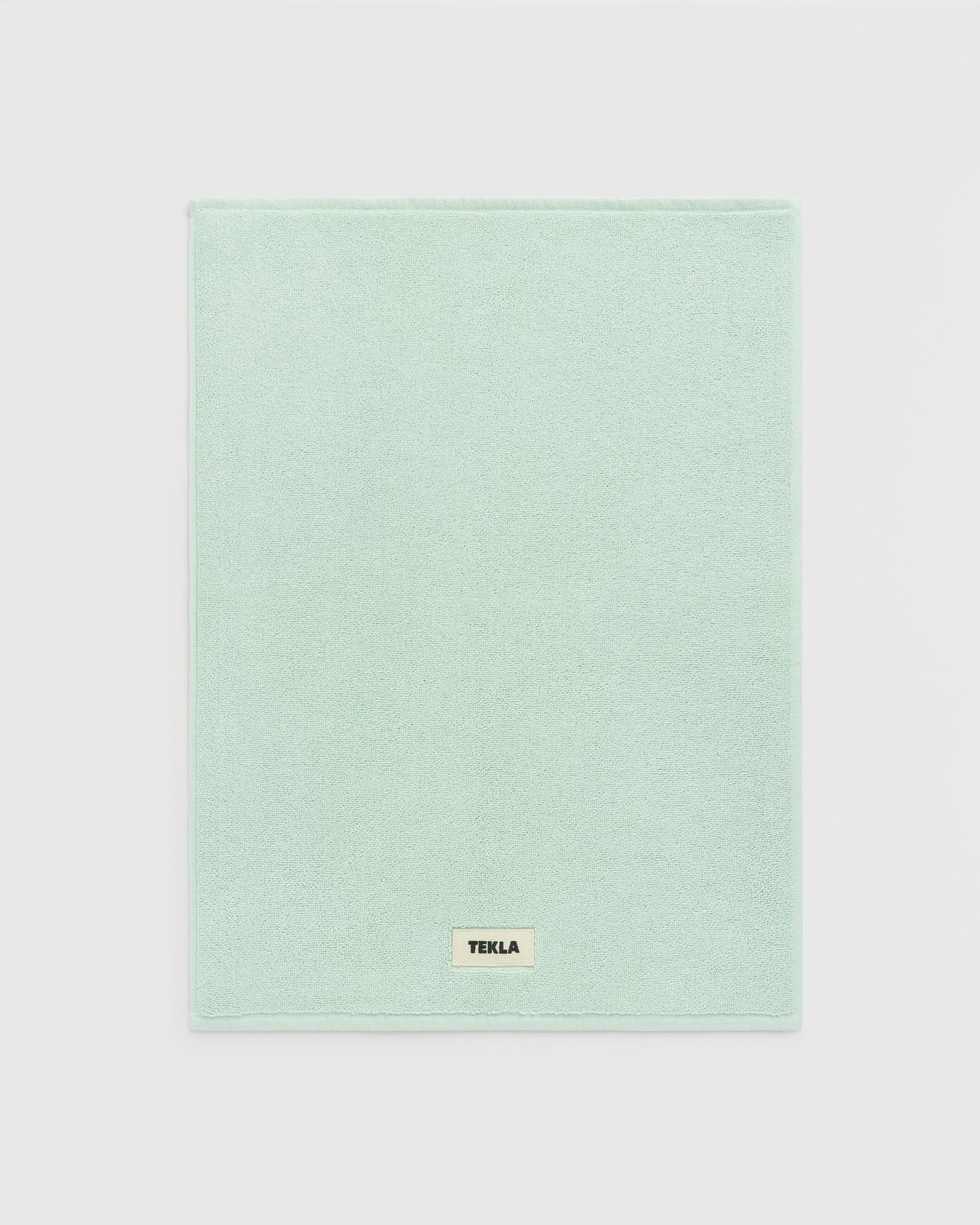 Light green towel with a brand label on a light gray background