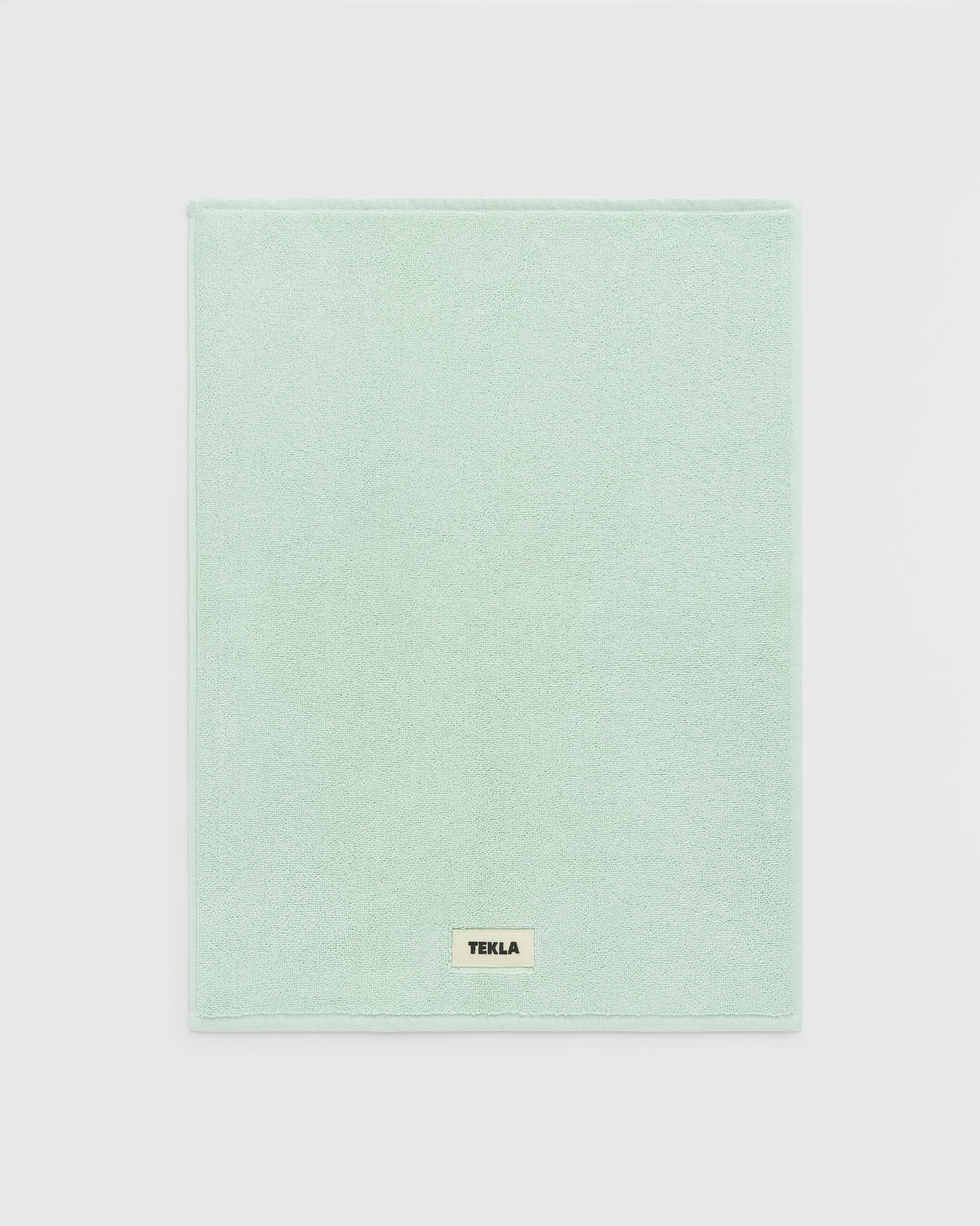 Light green towel with a brand label on a light gray background