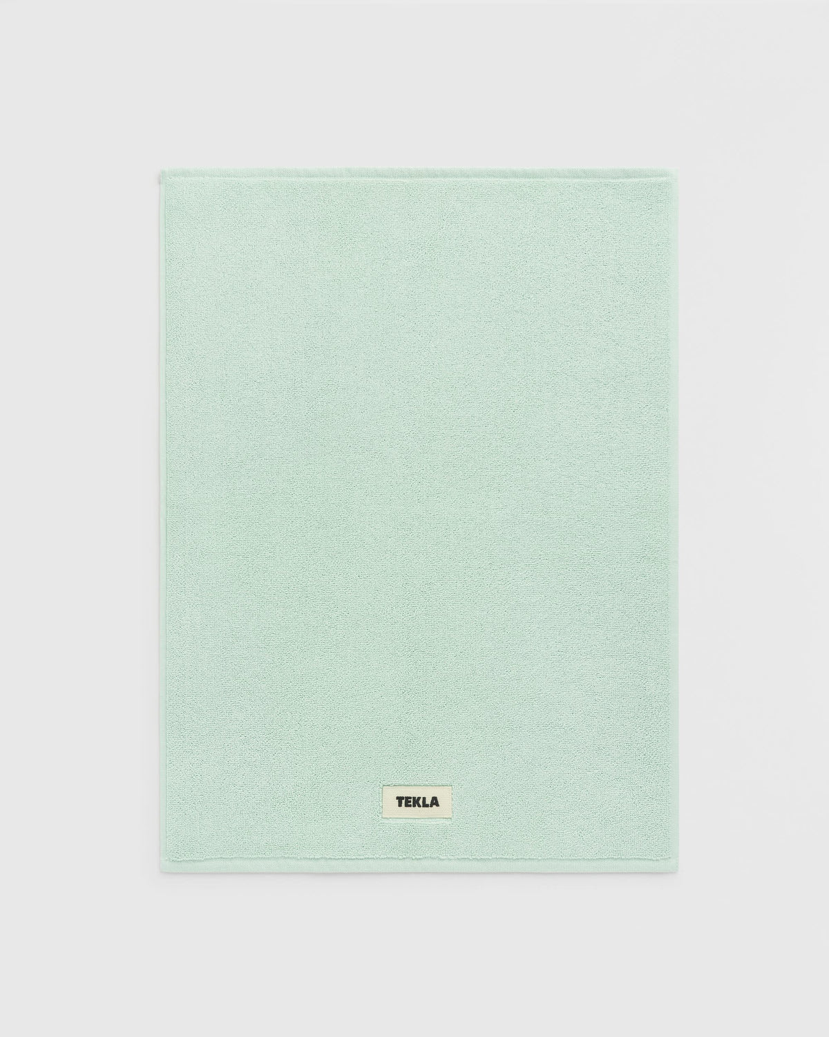 Light green towel with a brand label on a light gray background