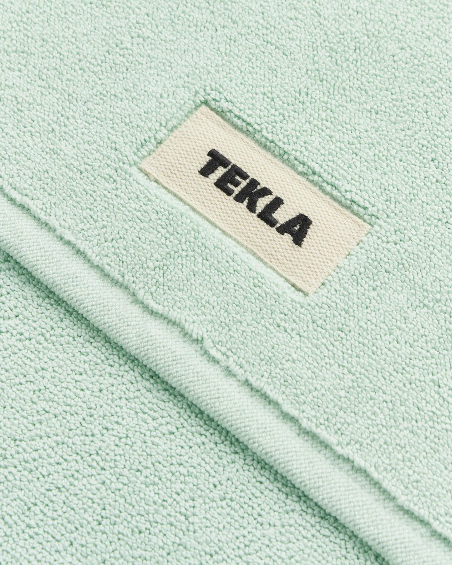 Close-up of a light green fabric with a 'Tekla' label.